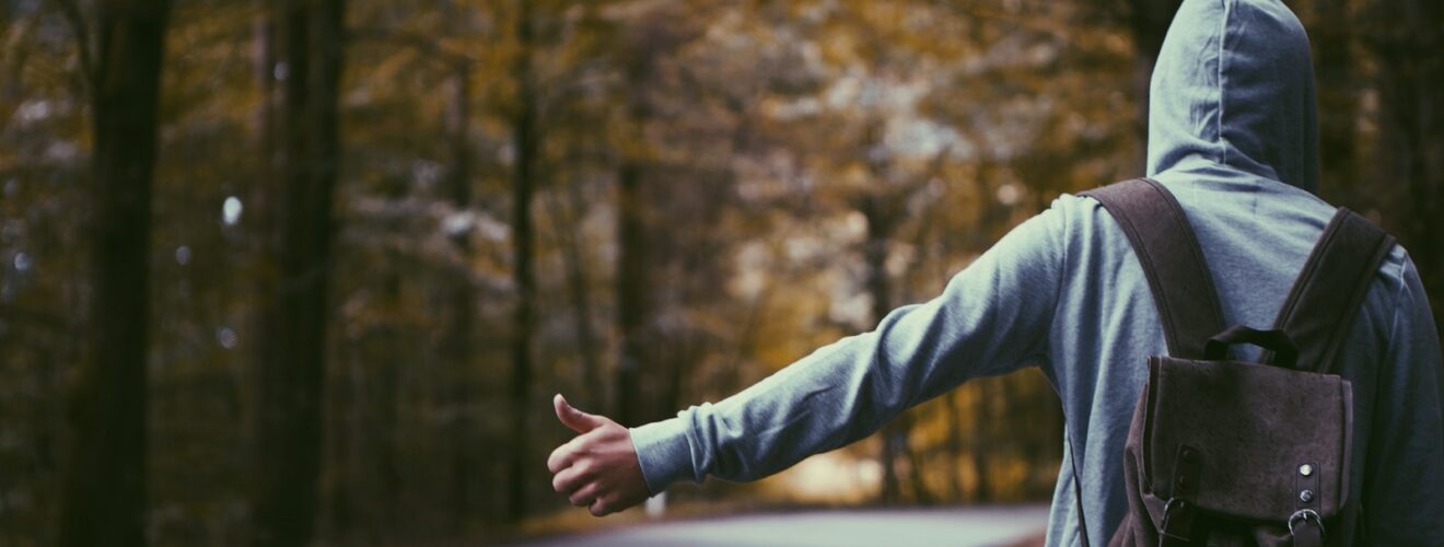 person standing beside road doing handsign